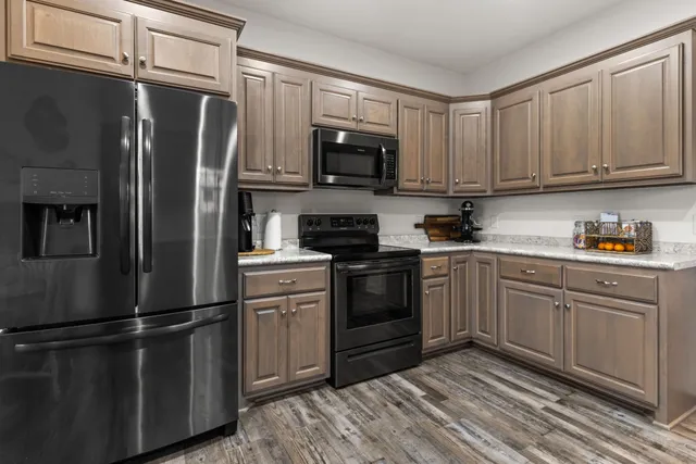 a kitchen with stainless steel appliances granite countertop a refrigerator stove a sink and dishwasher with wooden floor