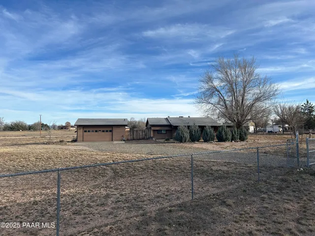 a view of a dry yard with wooden fence