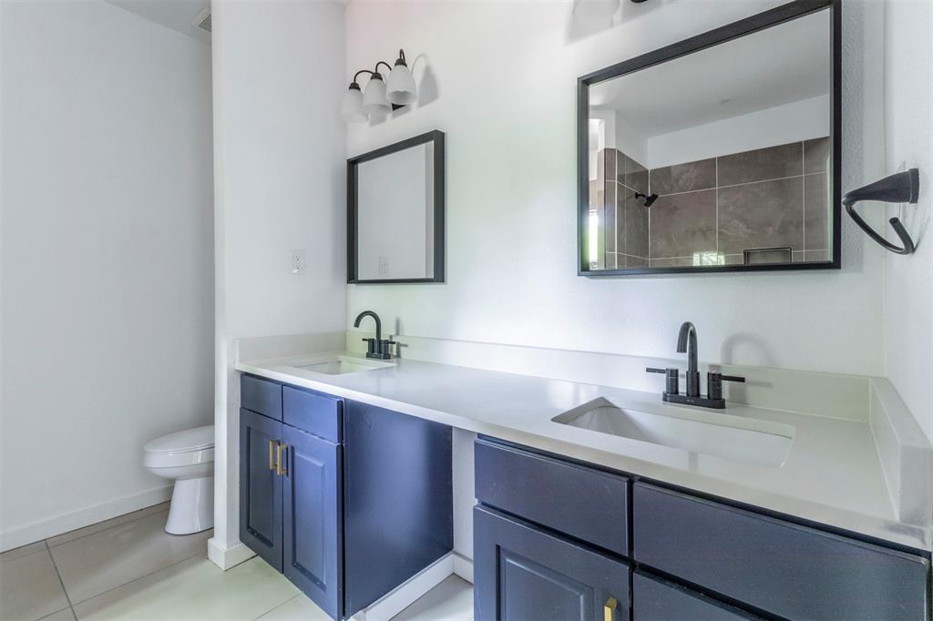 1014 Trinity Street Cleburne, TX 76031 - Photo 12 of 34 Bathroom with toilet, tile patterned flooring, double vanity, a shower, and baseboards