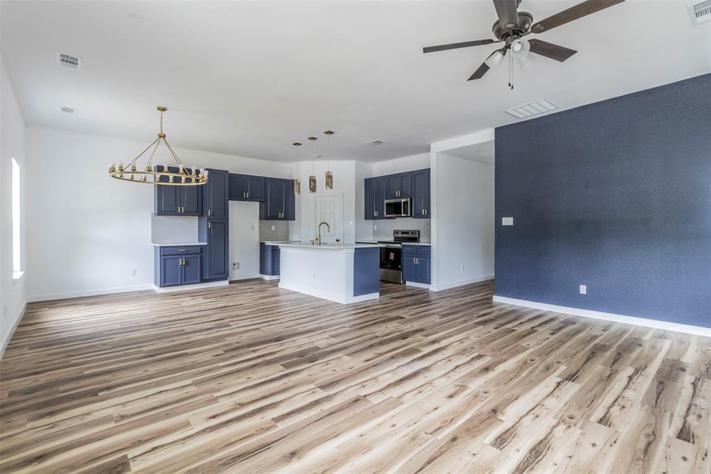 1014 Trinity Street Cleburne, TX 76031 - Photo 3 of 34 Unfurnished living room with light wood-style flooring, a sink, baseboards, ceiling fan, and a chandelier