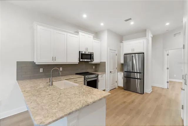 a kitchen with a refrigerator sink and cabinets
