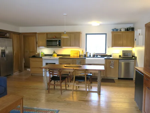 a kitchen with stainless steel appliances kitchen island granite countertop a table chairs and a refrigerator