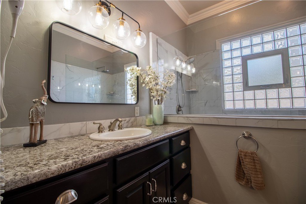 33699 Spring Brook Circle Temecula, CA 92592 - Photo 41 of 83 a bathroom with a granite countertop sink a large mirror and vanity