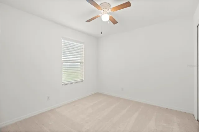 an empty room with a window and a fan