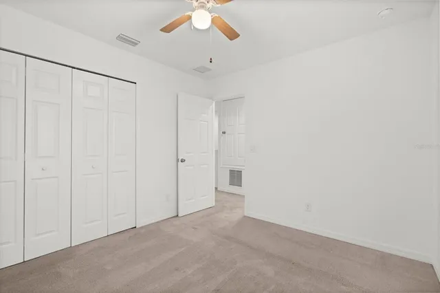 an empty room with a ceiling fan and a window