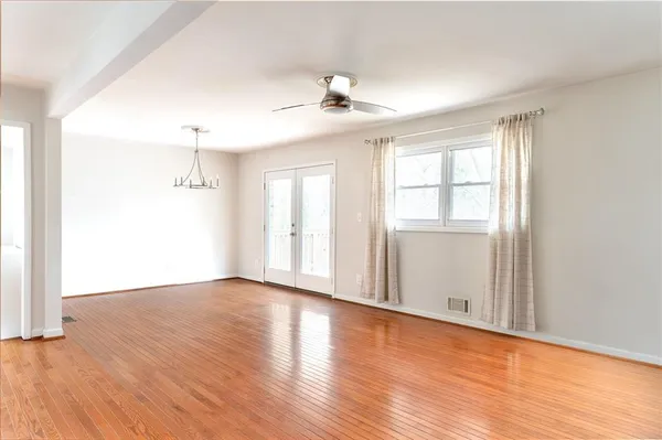 a view of an empty room with wooden floor and a window