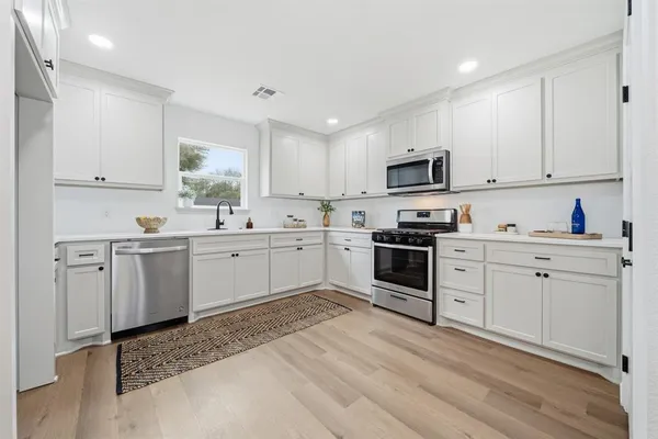 a kitchen with cabinets stainless steel appliances and a window