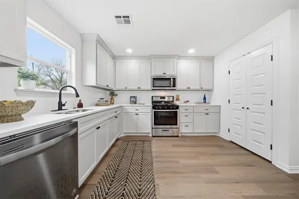 a kitchen with white cabinets and appliances