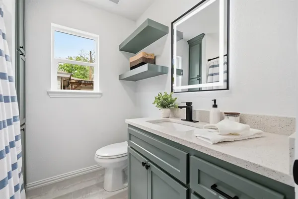a bathroom with a granite countertop sink toilet and a mirror