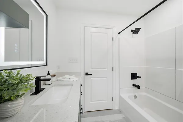 a bathroom with a bathtub shower sink and vanity