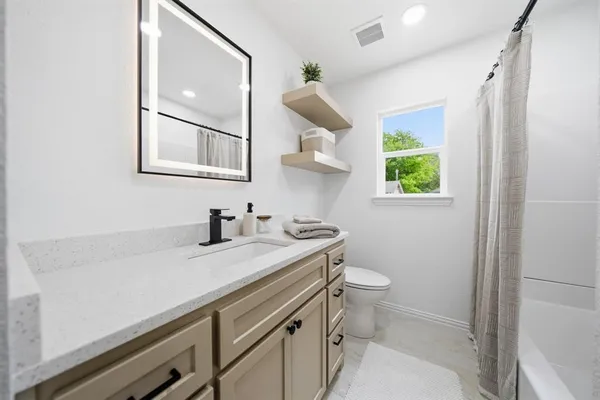 a bathroom with a granite countertop sink a toilet and a window