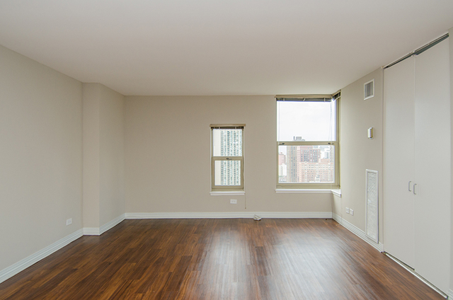 100 West Chestnut Street, Unit 1008 Chicago, IL 60610 - Photo 8 of 10 an empty room with wooden floor and windows