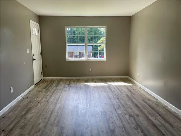 an empty room with wooden floor and windows