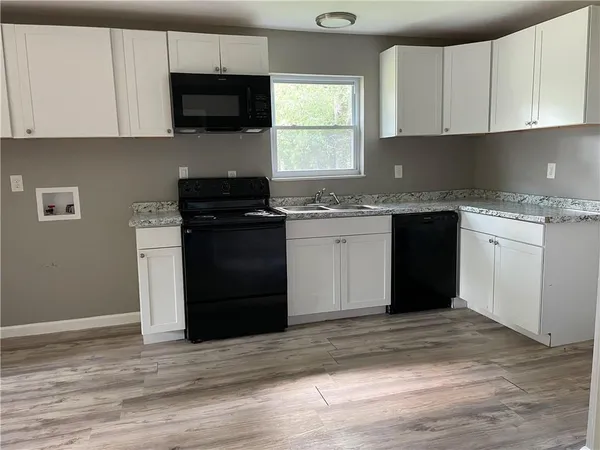 a kitchen with granite countertop a stove top oven a sink dishwasher and a refrigerator with wooden floor