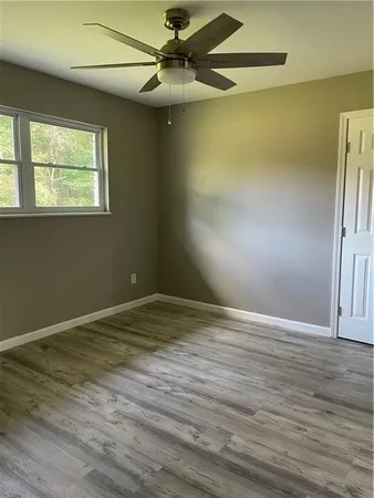 a view of an empty room with wooden floor and a window
