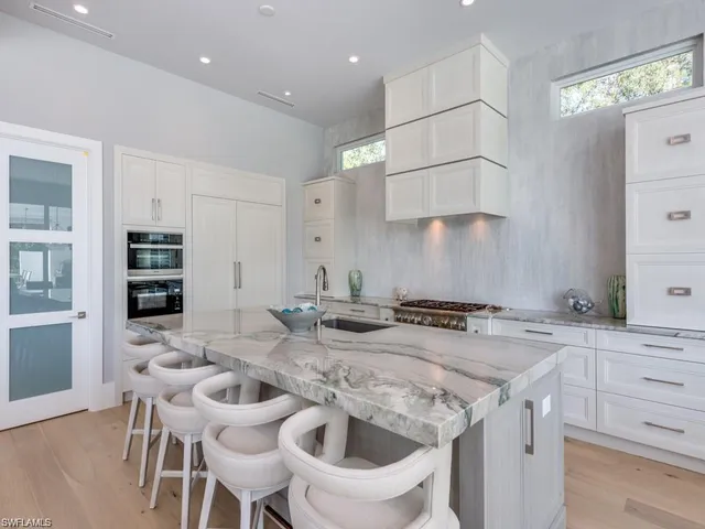 a kitchen that has a sink a stove and chairs