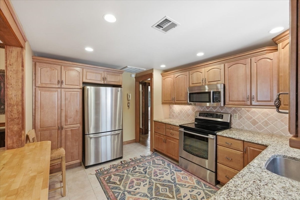 7 West Street Needham, MA 02494 - Photo 13 of 36 a kitchen with granite countertop a refrigerator and a stove top oven