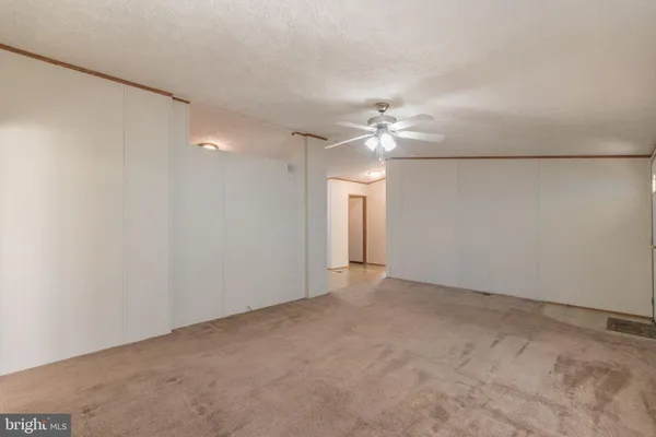 an empty room with a chandelier fan and windows