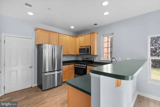 a kitchen with stainless steel appliances granite countertop a refrigerator a sink dishwasher a stove and a refrigerator with wooden floor