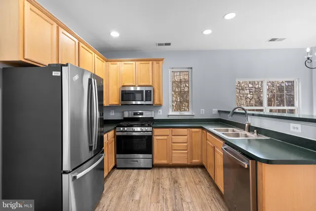 a kitchen with stainless steel appliances granite countertop a refrigerator a sink a stove a washer dryer and a refrigerator