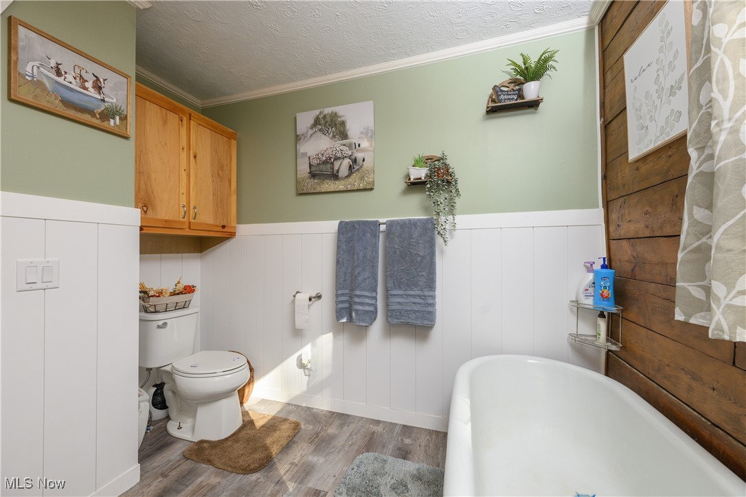 33201 Host Road Bowerston, OH 44695 - Photo 16 of 30 Bathroom with ornamental molding, a tub, a textured ceiling, hardwood / wood-style flooring, and toilet