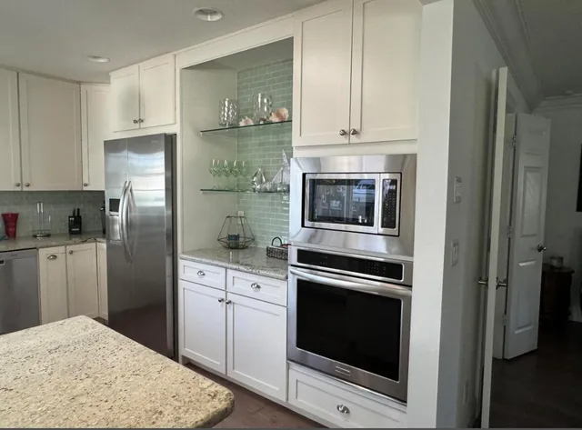 a kitchen with granite countertop white cabinets and stainless steel appliances