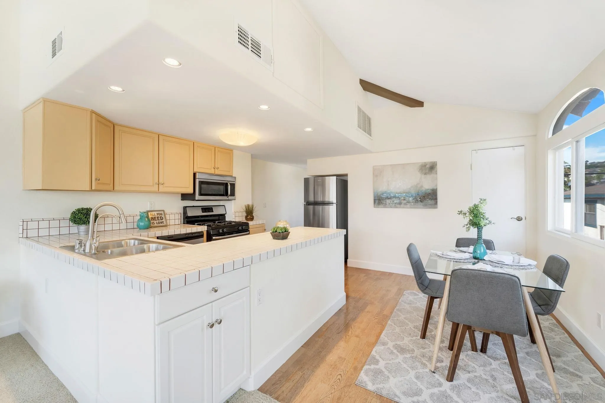 914 Agate Street, Unit E San Diego, CA 92109 - Photo 8 of 24 a kitchen with stainless steel appliances granite countertop a stove top oven a sink a dining table and chairs with white cabinets