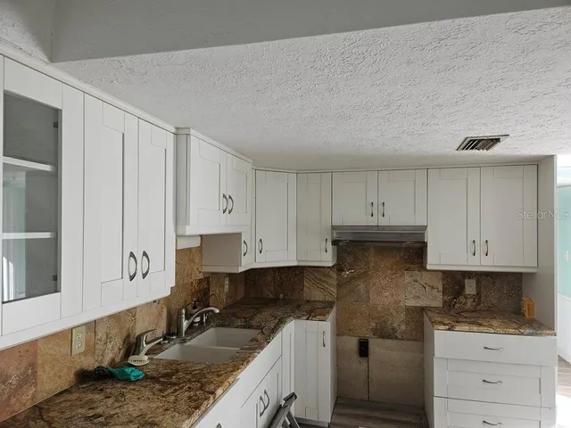 a kitchen with granite countertop a sink stove and cabinets