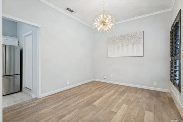 an empty room with wooden floor chandelier fan and windows