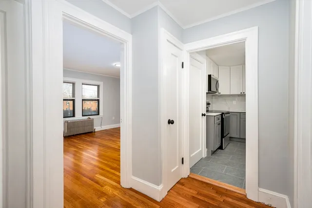 a view of a hallway with wooden floor and a living room