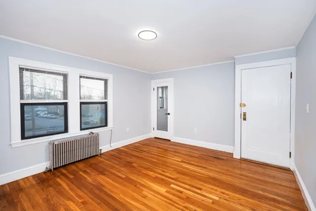 a view of an empty room with a window and wooden floor