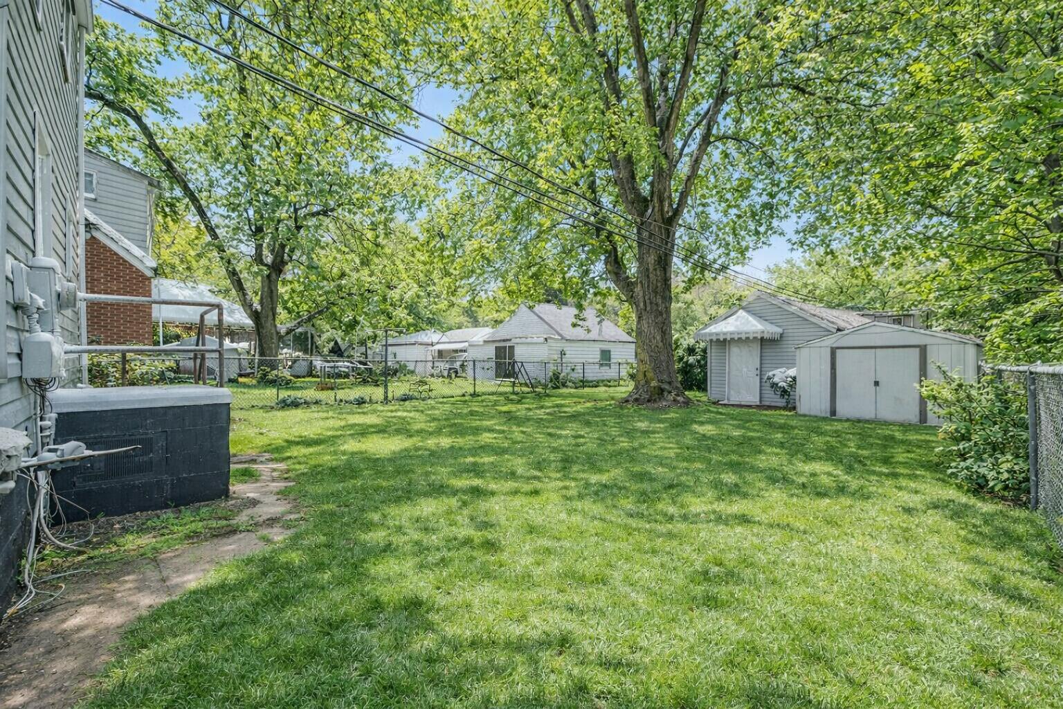 4810 Monroe Street Gary, IN 46408 - Photo 18 of 19 a backyard of a house with table and chairs plants and large tree