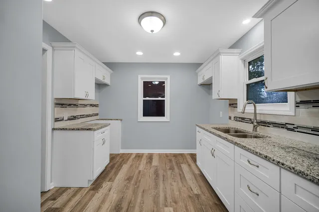 a kitchen with granite countertop a sink stove and cabinets