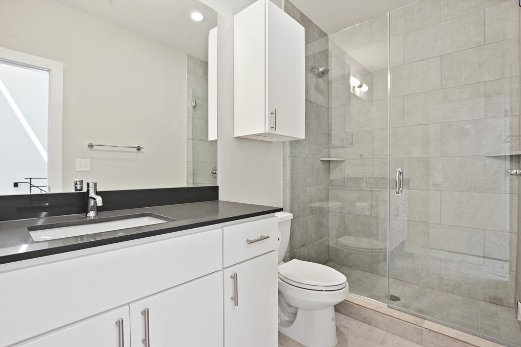2002 East 7th Street, Unit 246 Austin, TX 78702 - Photo 21 of 25 a bathroom with a granite countertop sink a toilet and a mirror