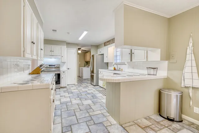 a room with kitchen island white cabinets and window