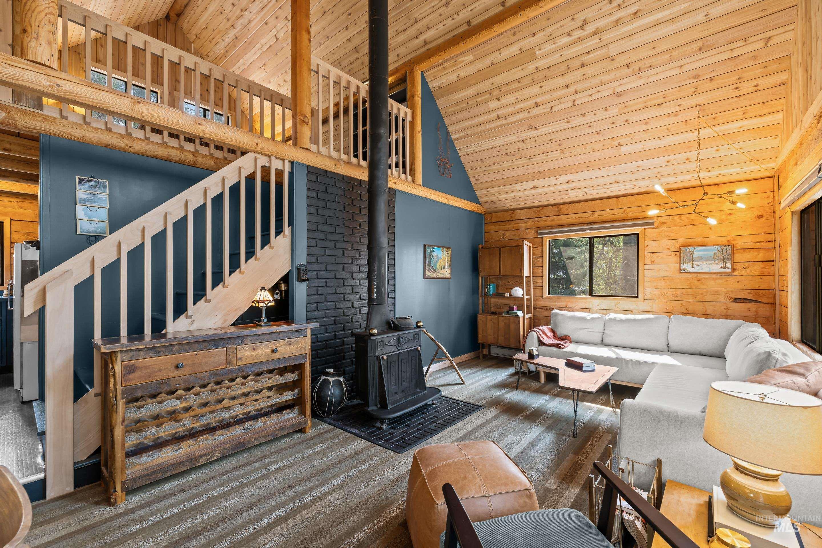 73 Rainbow Ridge Road Garden Valley, ID 83622 - Photo 24 of 49 Vaulted wood-paneled ceiling, wood-finish flooring, built-in staircase, wood-burning stove with brick surround, and exposed log beams