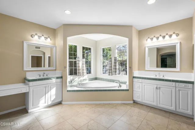 a spacious bathroom with a tub sink and mirror