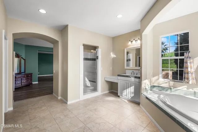 a large white bathroom with a granite countertop sink and a large mirror