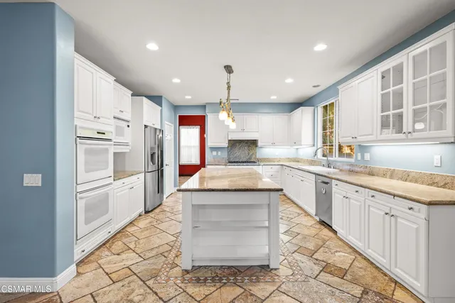 a large kitchen with granite countertop a large stove a sink dishwasher and a refrigerator