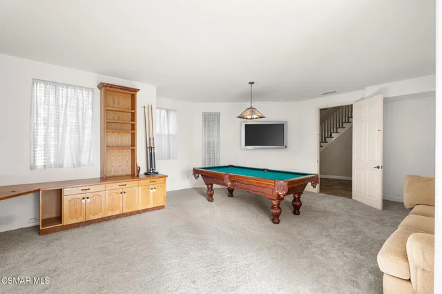 a living room with furniture pool table and windows