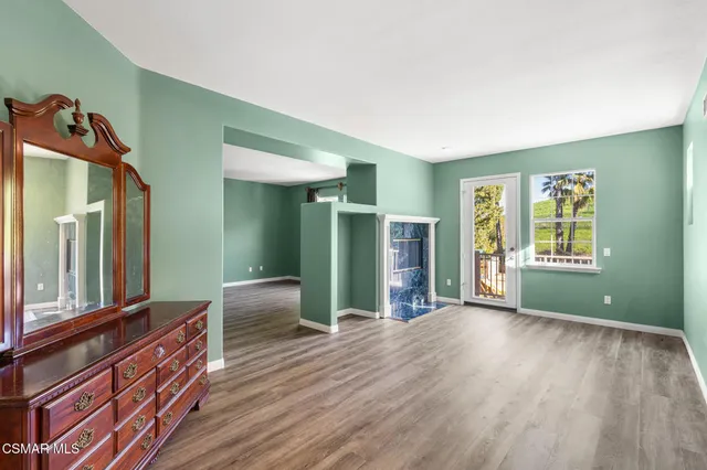 a view of an empty room with window and wooden floor