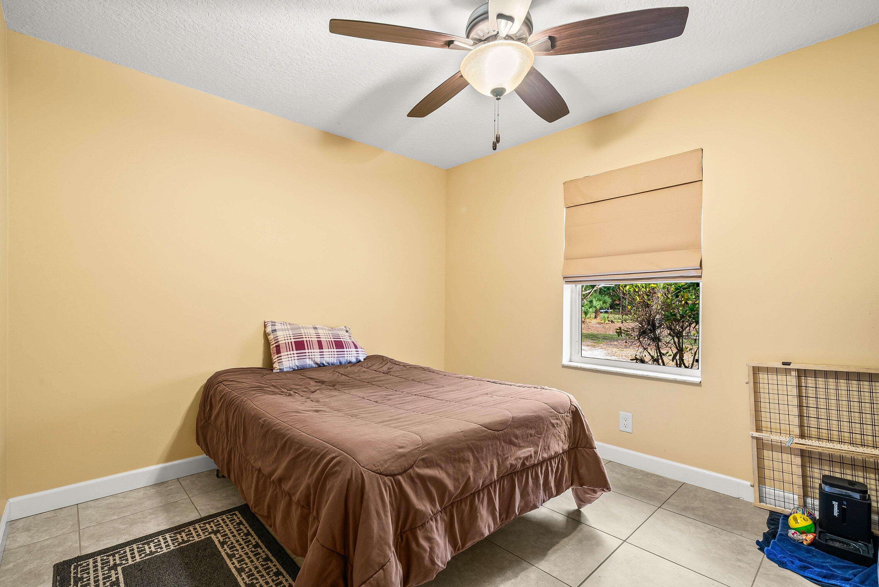 2195 F Road Loxahatchee Groves, FL 33470 - Photo 14 of 54 a bedroom with a bed and a chandelier
