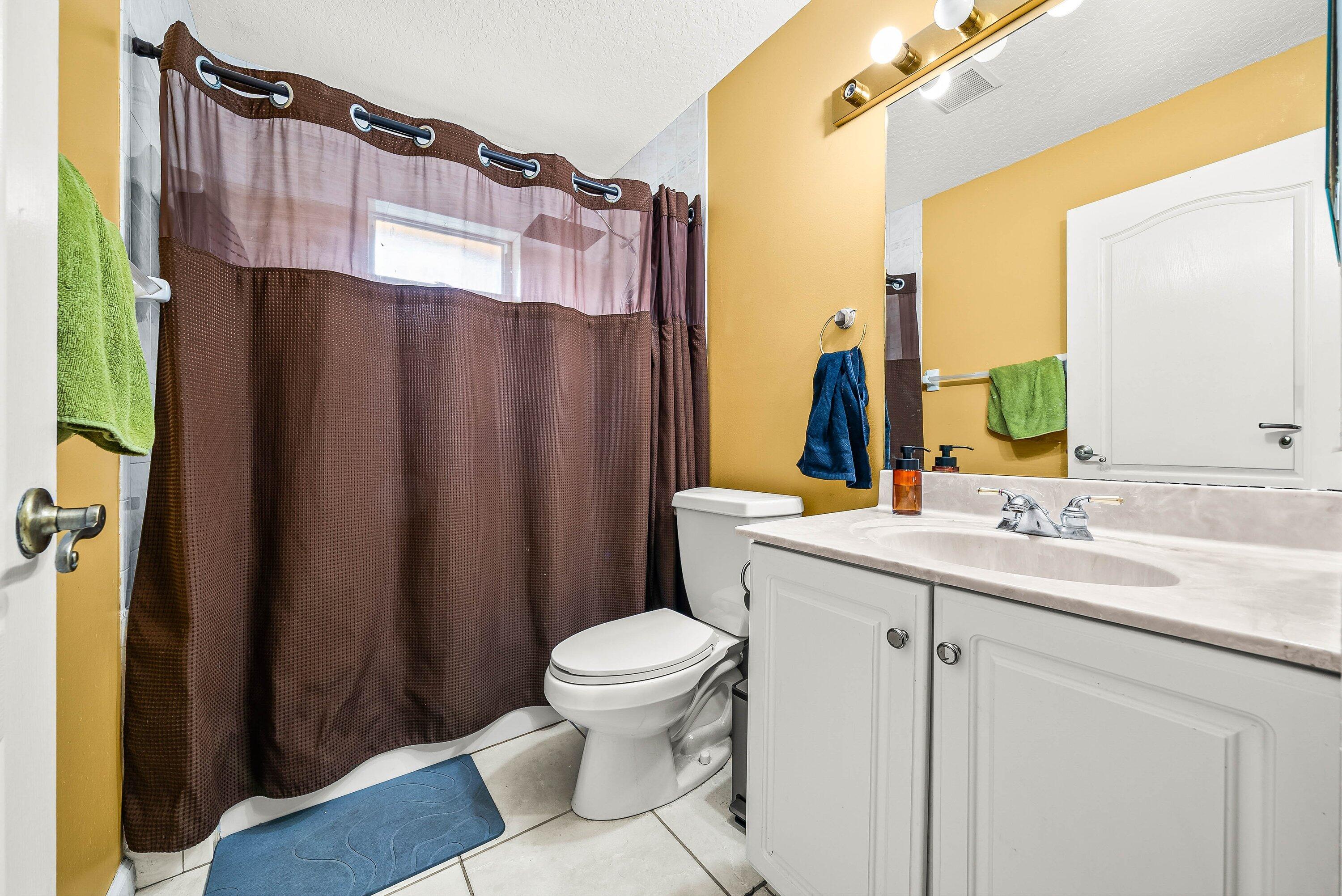 2195 F Road Loxahatchee Groves, FL 33470 - Photo 15 of 54 a bathroom with a sink a toilet a mirror and shower curtain