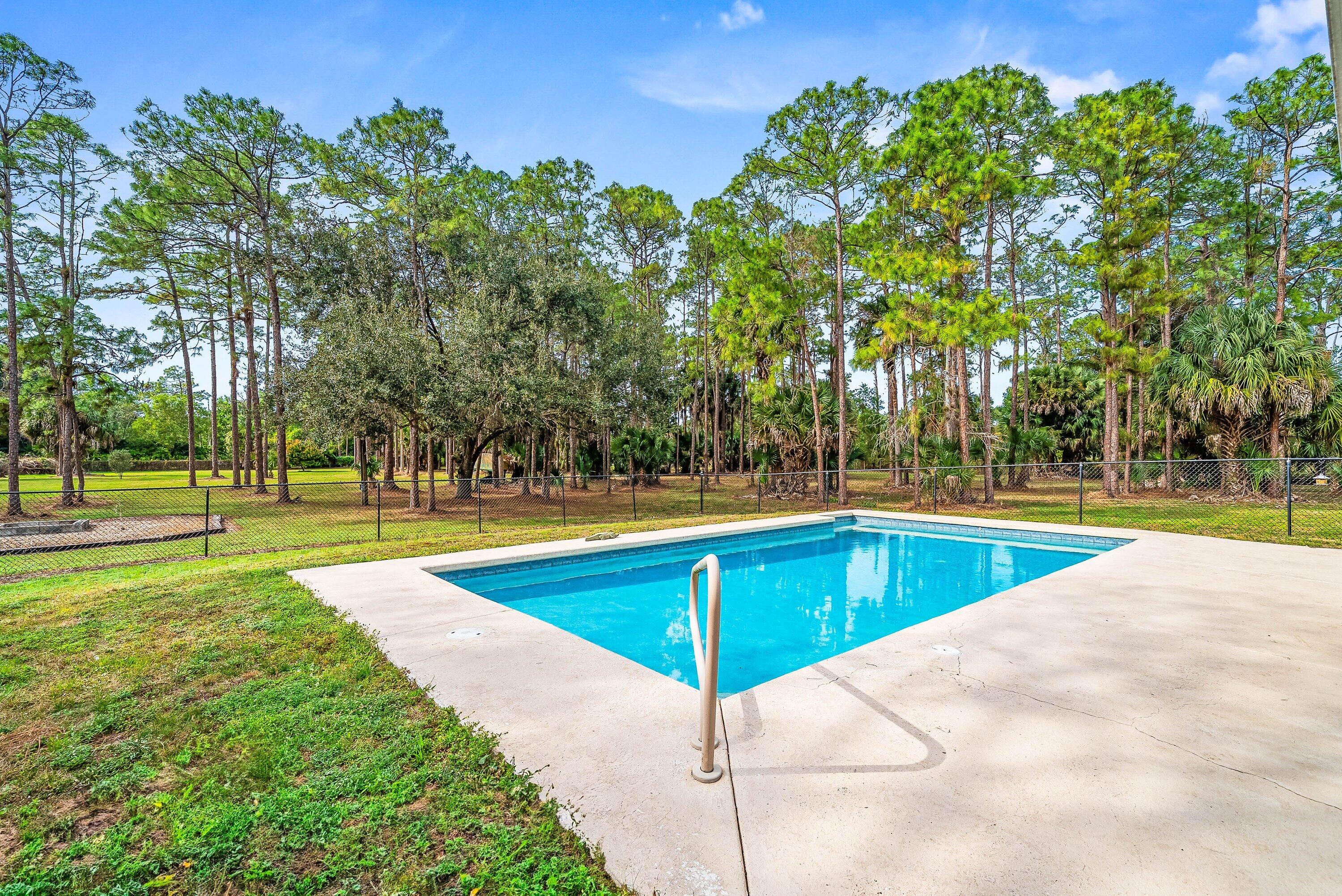 2195 F Road Loxahatchee Groves, FL 33470 - Photo 24 of 54 a view of a swimming pool with an outdoor space and seating area