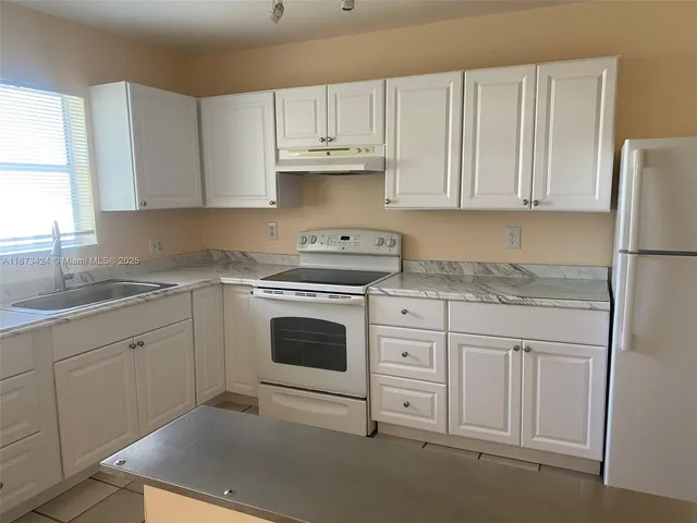 a kitchen with granite countertop white cabinets and white appliances