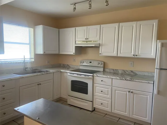 a kitchen with cabinets appliances a sink and a window