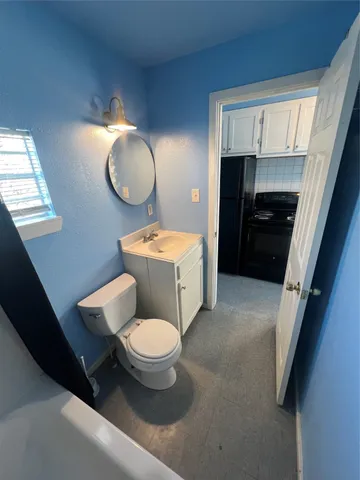 a large bedroom with a bed and view of kitchen