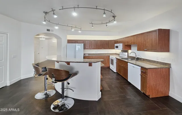 a kitchen with stainless steel appliances granite countertop a sink a stove and chairs with wooden floor