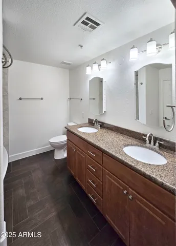 a bathroom with a granite countertop sink a toilet and a mirror
