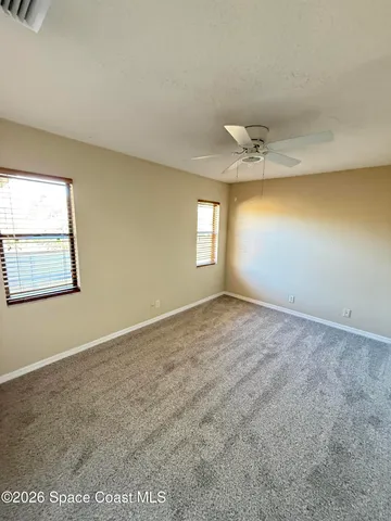 an empty room with windows and ceiling fan